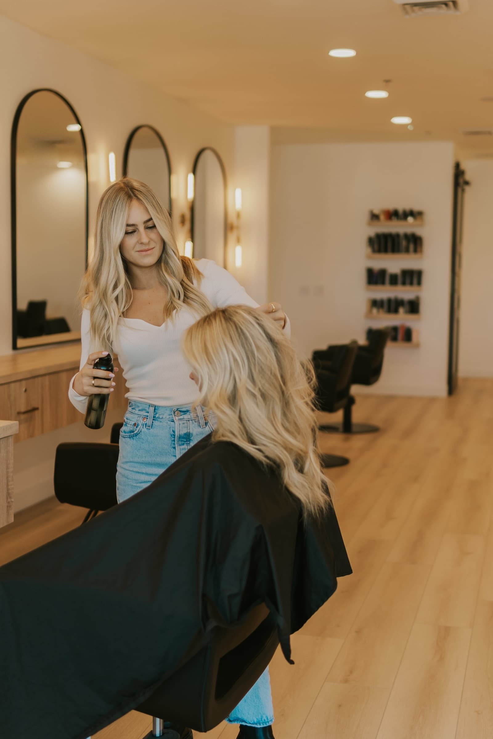 A stylist finishing a client's blonde waves at the styling station.