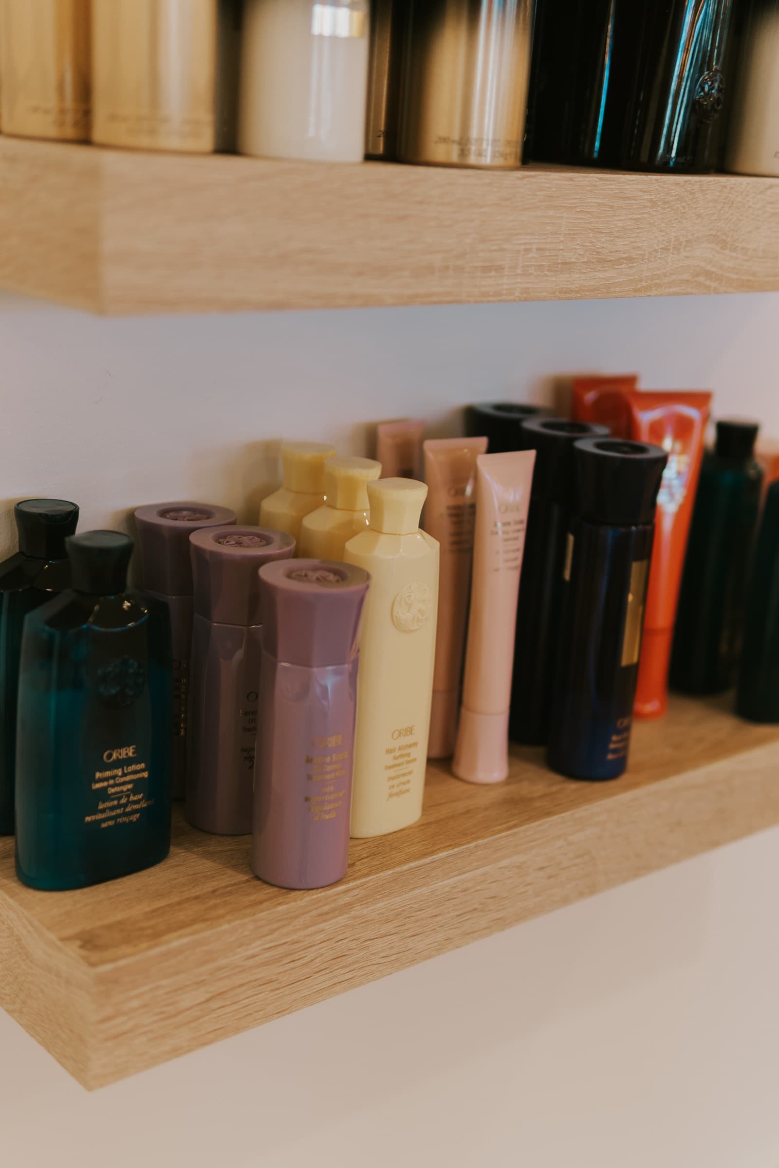 Oribe bottles lined up along the oak retail shelving in the salon.