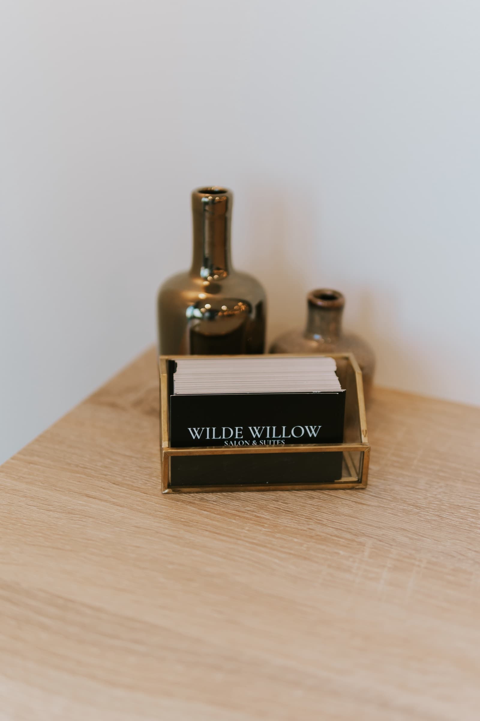 Wilde Willow business cards in a brass holder on the oak reception counter.